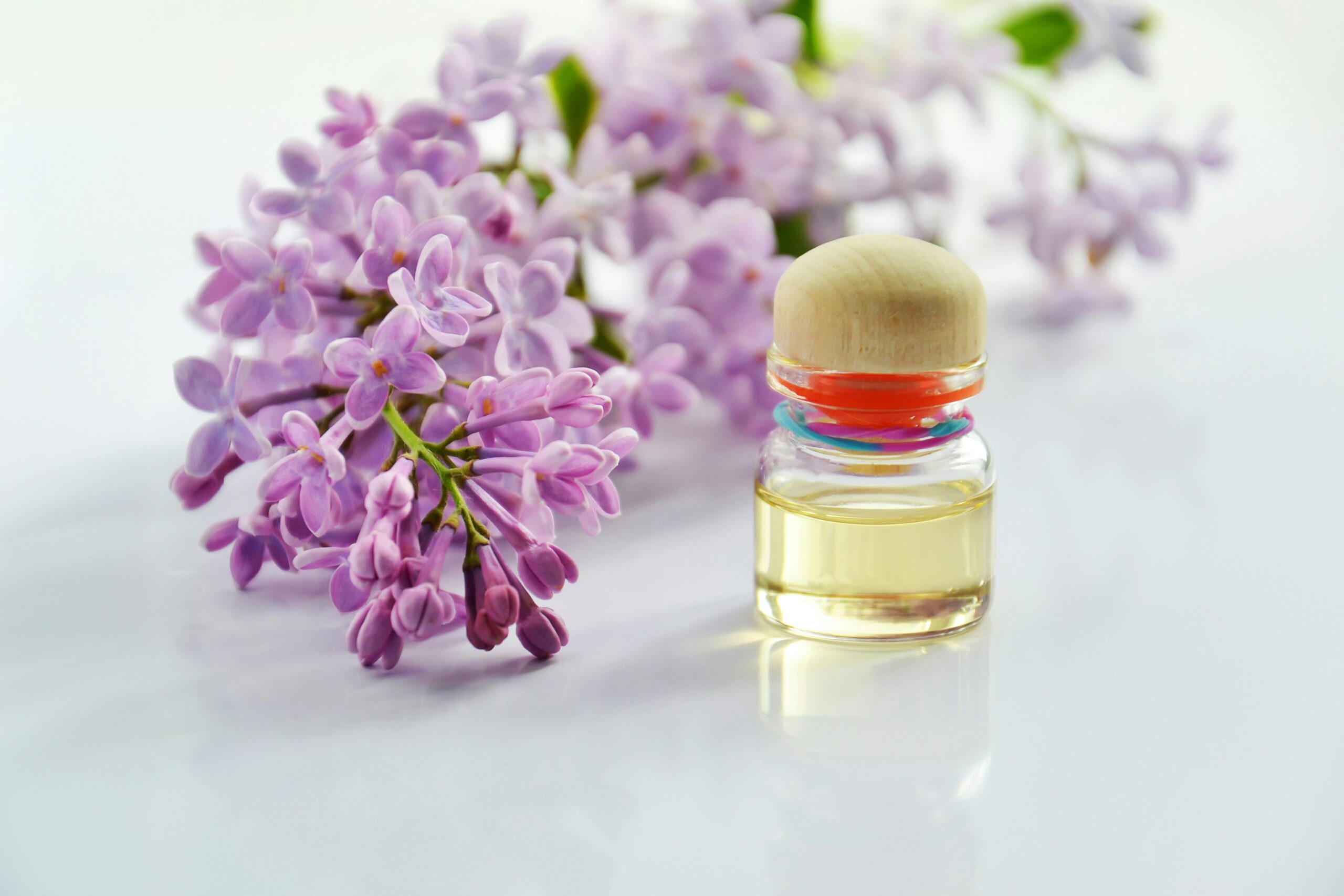 A flat lay displaying essential oils, dried lavender, and other aromatherapy items on a woven mat.